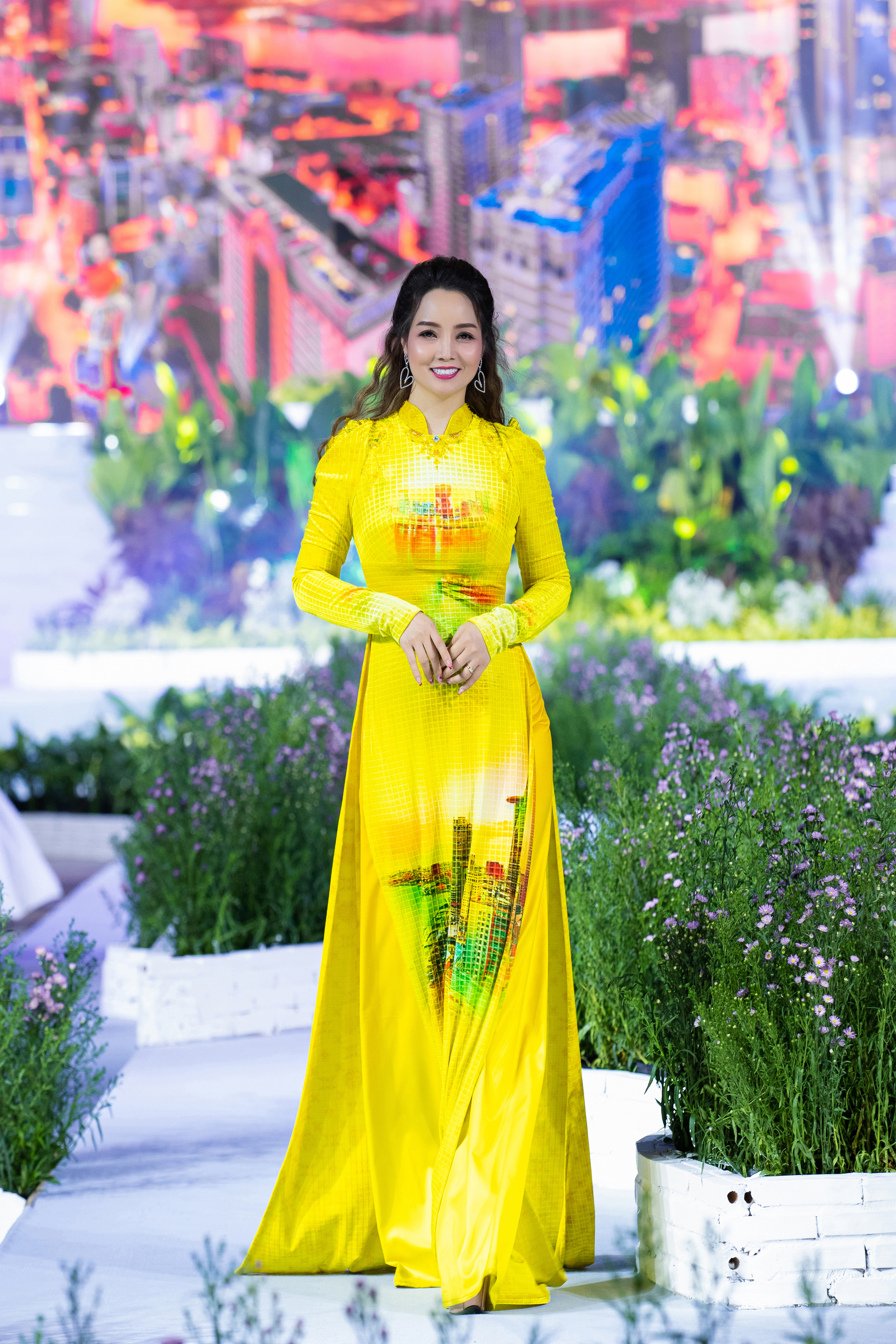 Thạc sĩ, diễn vi&ecirc;n, nh&agrave; sản xuất Mai Thu Huyền trong một thiết kế Ngọc Viễn Đ&ocirc;ng thể hiện vẻ đẹp của th&agrave;nh phố Hồ Ch&iacute; Minh ven s&ocirc;ng tr&ecirc;n nền chất liệu nhung &aacute;nh v&agrave;ng được xử l&yacute; theo phong c&aacute;ch mosaic độc đ&aacute;o, sang trọng.