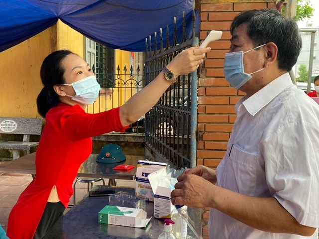 Cử tri được đo th&acirc;n nhiệt, rửa tay s&aacute;t khuẩn trước khi v&agrave;o bầu cử. &nbsp;