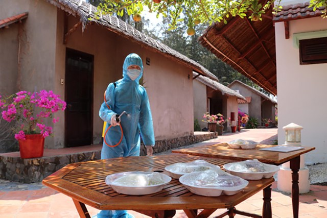 Nh&acirc;n vi&ecirc;n khử khuẩn khu vực để đồ ăn cho người c&aacute;ch ly sau khi d&ugrave;ng xong tại một resort ở Cần Giờ trong đợt dịch v&agrave;o th&aacute;ng 3/2020 - Ảnh: Ngọc Phượng.