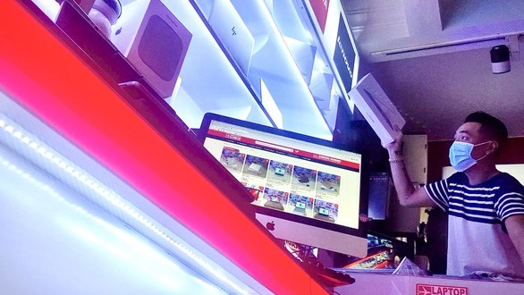 Nh&acirc;n vi&ecirc;n một cửa h&agrave;ng b&aacute;n đồ x&aacute;ch tay lấy hộp laptop ch&agrave;o b&aacute;n với gi&aacute; rẻ cho kh&aacute;ch - Ảnh: B&ocirc;ng Mai