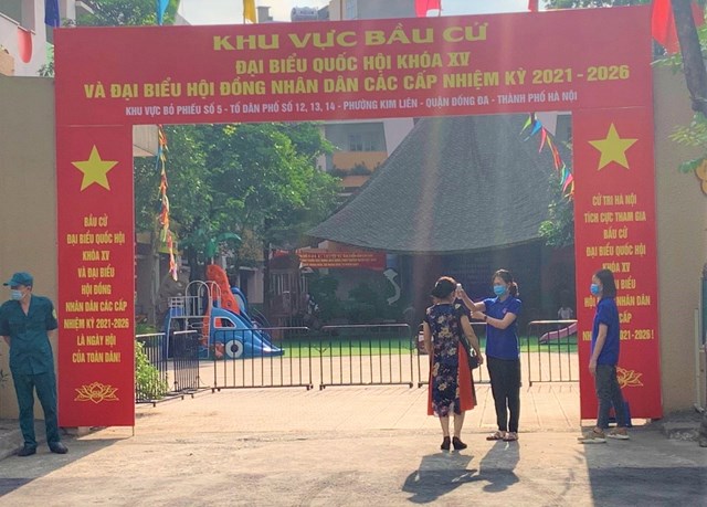 Tại khu vực bỏ phiếu phường Kim Li&ecirc;n, quận Đống Đa, ngay từ ph&iacute;a cổng ra v&agrave;o c&aacute;c cử tri đ&atilde; được đo th&acirc;n nhiệt v&agrave; hướng được hướng dẫn rửa tay trước khi v&agrave;o bầu cử theo đ&uacute;ng như nguy&ecirc;n tắc ph&ograve;ng v&agrave; chống dịch. Ảnh: Ph&ugrave;ng Quy&ecirc;n &ndash; Huyền Mai