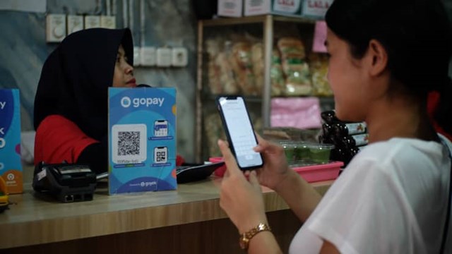 Một người phụ nữ đang sử dụng ứng dụng thanh to&aacute;n điện tử của GoTo. Ảnh: GoTo